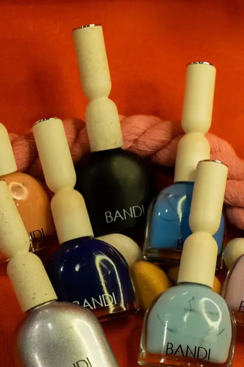 A cluster of BANDI polish bottles in several colours on an orange cloth.