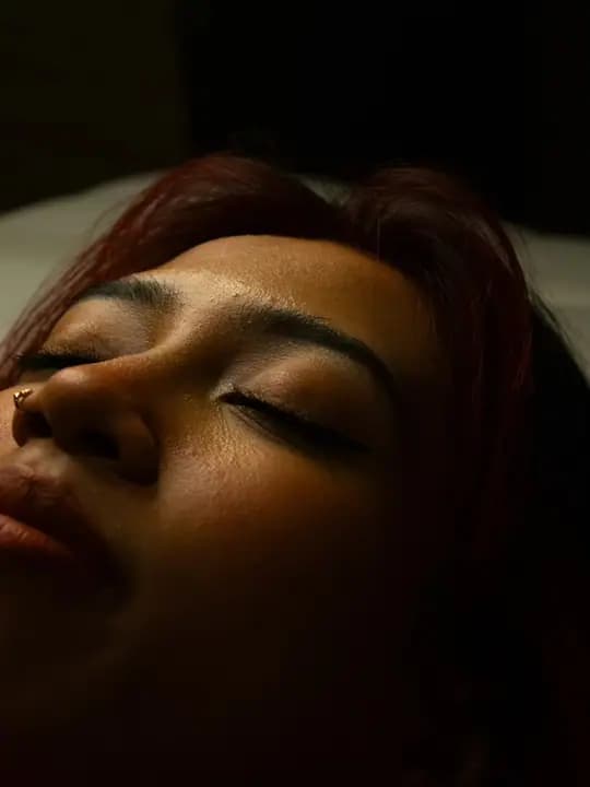 Close-up of a person with closed eyes, showing the lashes in warm light.