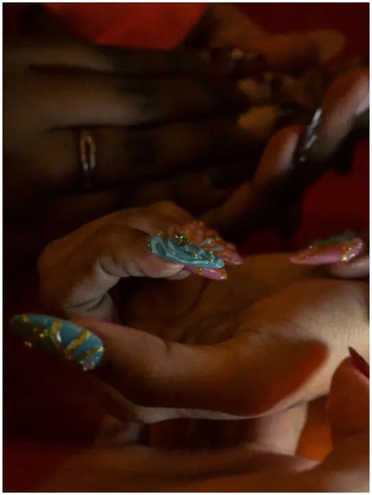 Close-up of teal, pink, and gold nail art.