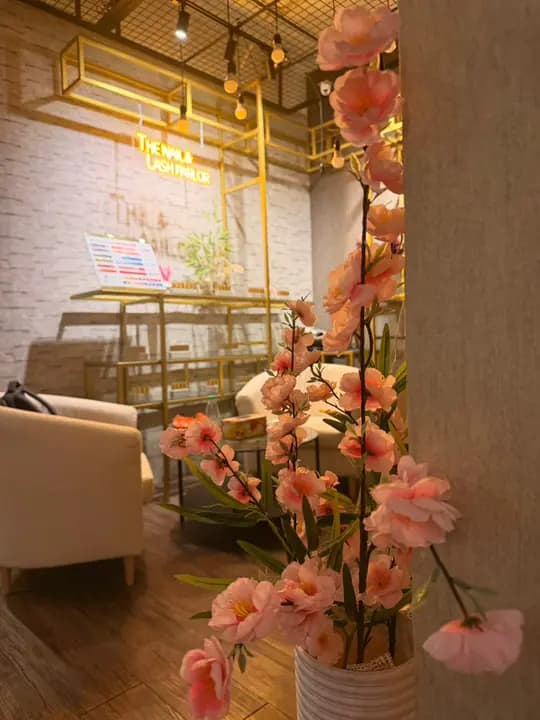 Pink blossoms in front of the lounge, with the neon parlor sign on the stone wall.