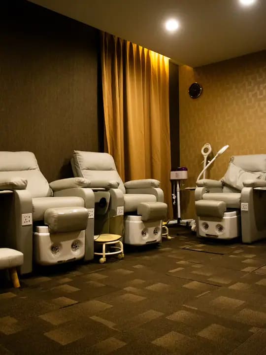 Pedicure chairs in warm light, with a gold curtain and task lamps.