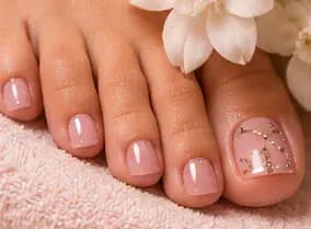 Illustrative study of a pedicure with pale pink polish and stones on the big toe. Not work from this parlor.