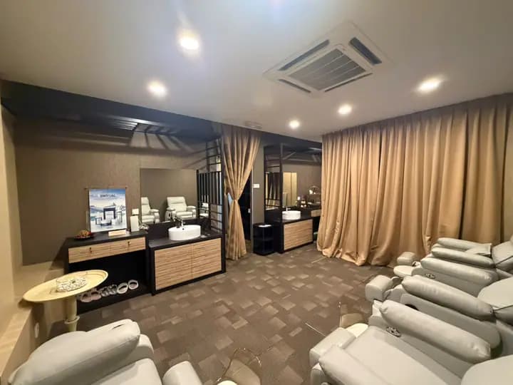 Treatment room with beige curtains, sinks, and pedicure chairs.