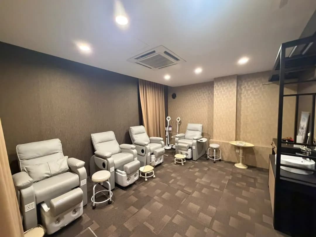 Four pale pedicure chairs with foot baths in a treatment room.